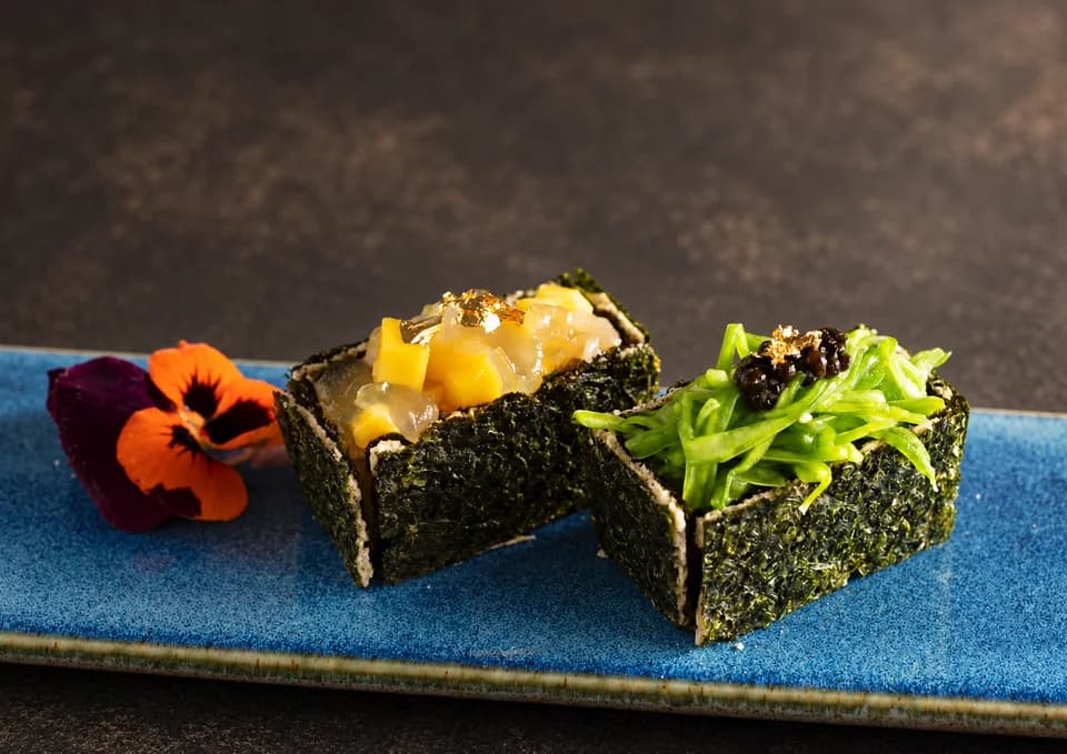 Plant-based sushi bites with mango, aloe and greens on a blue plate
