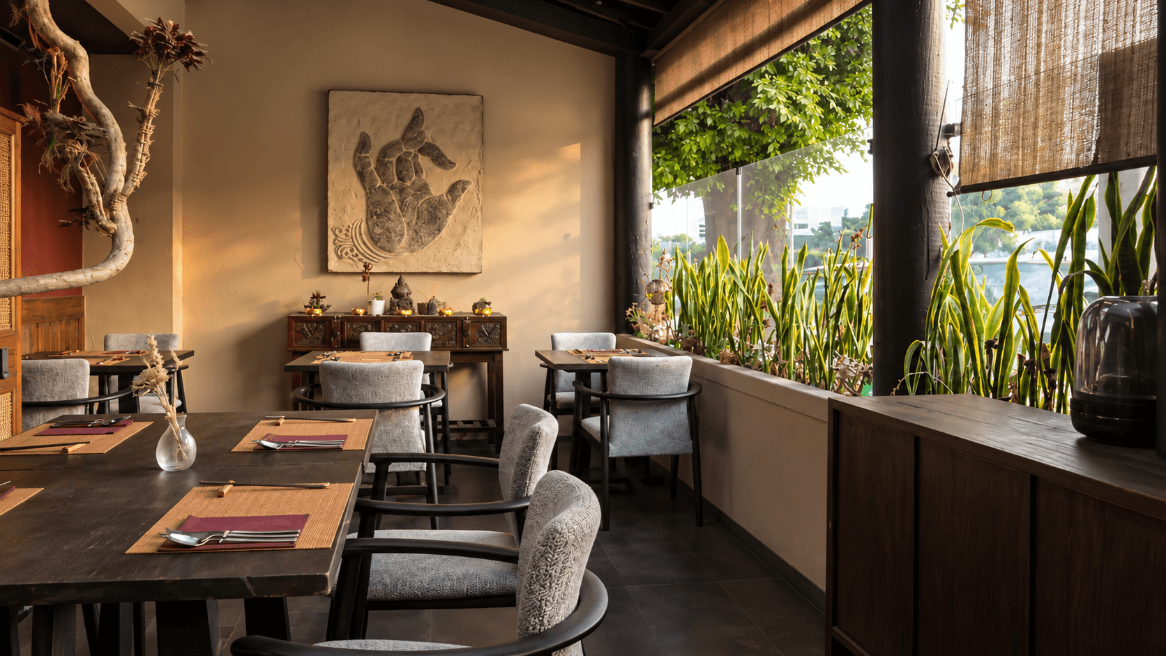 Warm dining room with Buddha hand artwork and plants beside sunlit windows