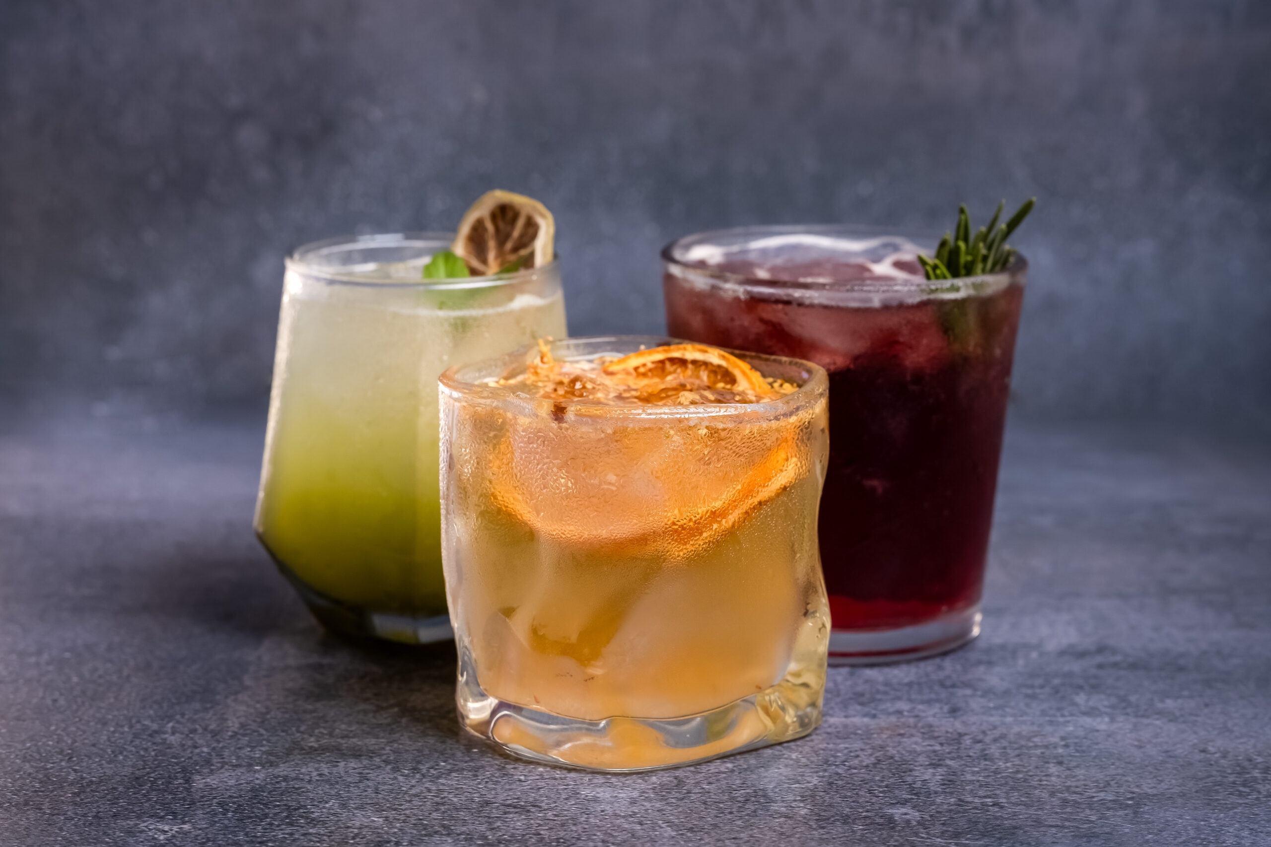 Three colorful drinks garnished with citrus and herbs at Taste of Beauty